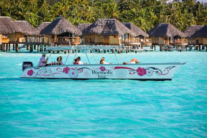 Three couples sailing on a Polynesian outrigger In Bora Bora
