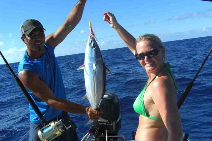 A client and a guide holding a fish during a fishing tour in Bora Bora