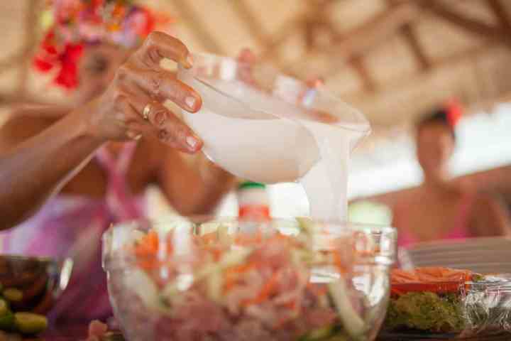 A woman pouring fresh coconut milk on fish raw