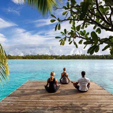 a group of people sitting on a bench next to a body of water