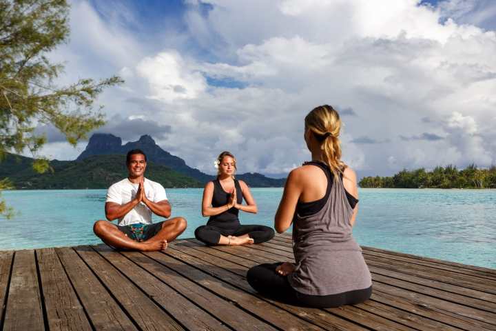 a woman sitting on a bench next to a body of water