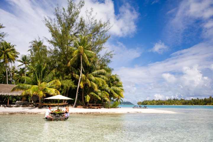 A couple having a lunch feet in the water on a motu in Bora Bora