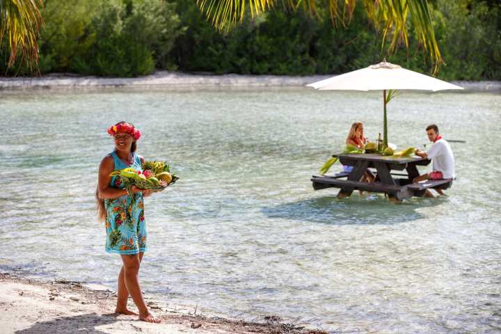 A couple having a lunch feet in the water on a motu in Bora Bora