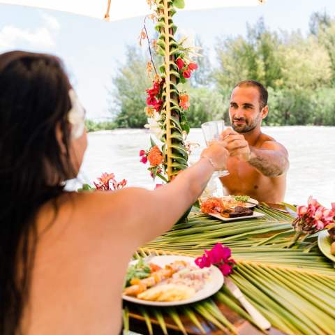 A couple having a lunch feet in the water on a motu in Bora Bora