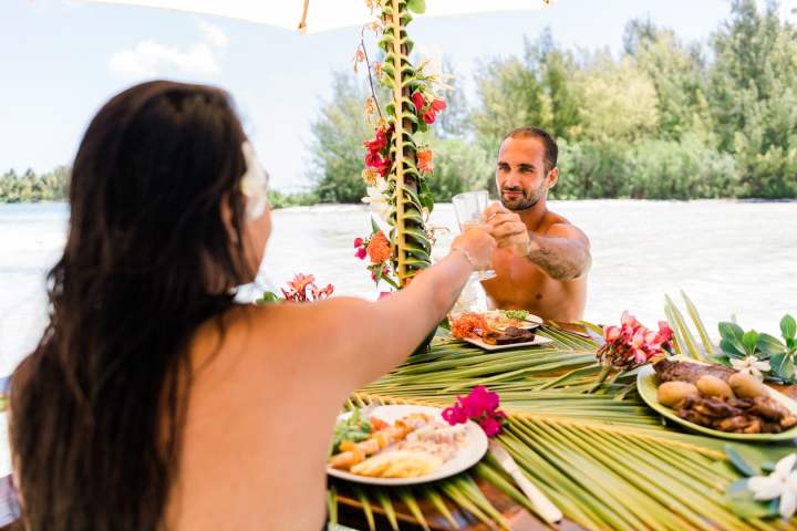 A couple having a lunch feet in the water on a motu in Bora Bora