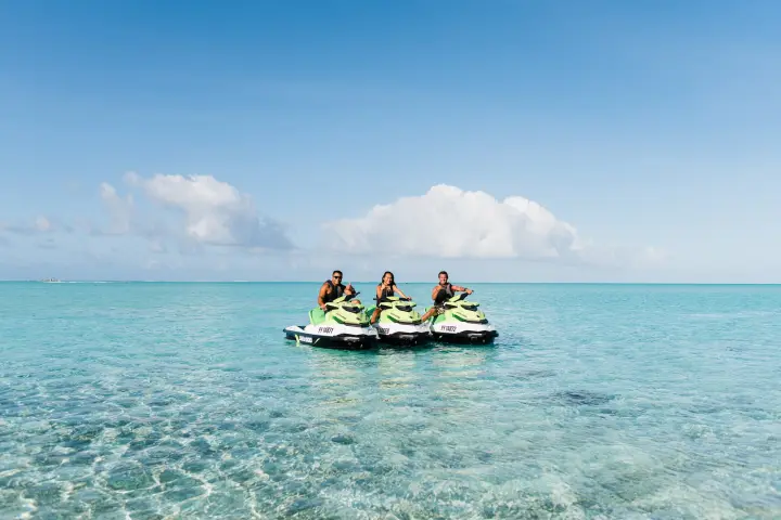 Two tourists jet skiing with a guide on Bora Bora lagoon