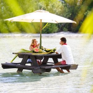 A couple having a lunch feet in the water on a motu in Bora Bora